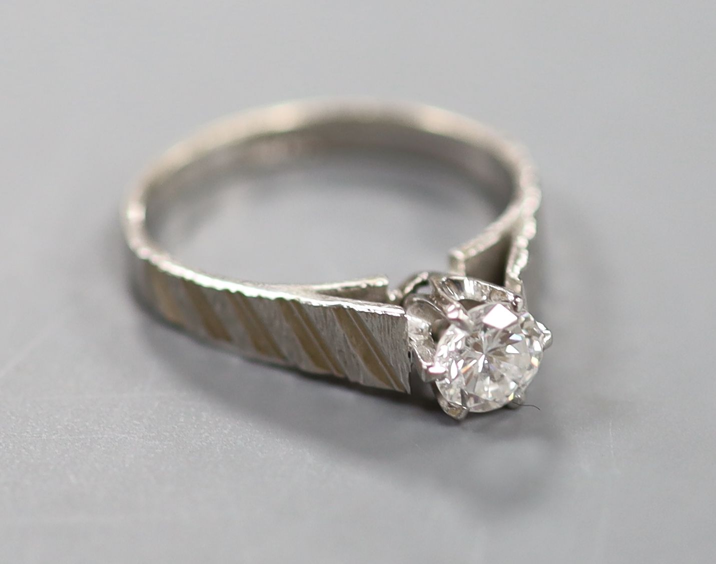 A modern 18ct white metal and solitaire diamond ring, with engraved shoulders